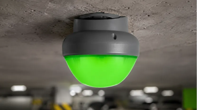 Close-up of a green LED parking space indicator mounted on a ceiling