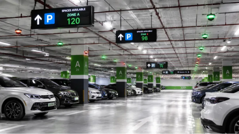Modern parking garage showing digital guidance screens and red or green LED space indicator lights